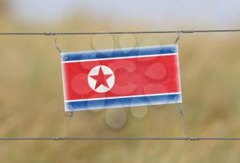 Border fence - Old plastic sign with a flag - North Korea