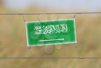 Border fence - Old plastic sign with a flag - Saudi Arabia