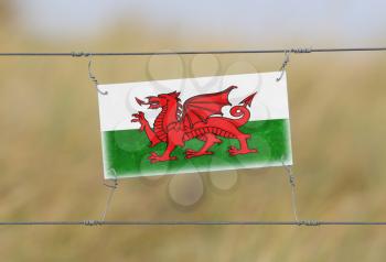 Border fence - Old plastic sign with a flag - Wales