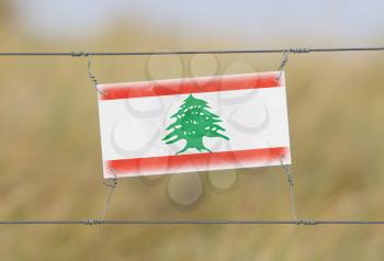 Border fence - Old plastic sign with a flag - Lebanon
