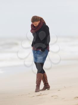 Pretty woman in stylish warm clothing at beach against