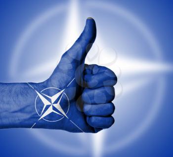 Closeup of male hand showing thumbs up sign against white background, NATO