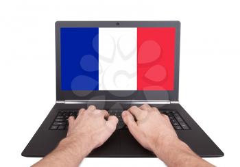 Hands working on laptop showing on the screen the flag of France