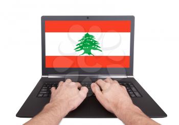 Hands working on laptop showing on the screen the flag of Lebanon