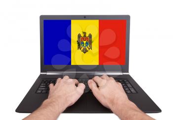Hands working on laptop showing on the screen the flag of Moldova