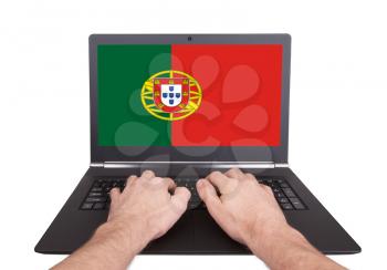 Hands working on laptop showing on the screen the flag of Portugal