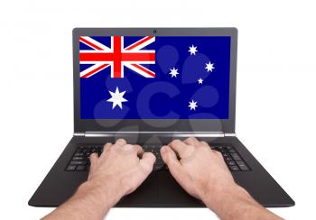 Hands working on laptop showing on the screen the flag of Australia