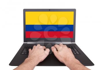Hands working on laptop showing on the screen the flag of Colombia