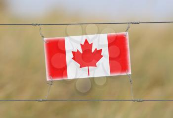 Border fence - Old plastic sign with a flag - Canada