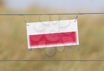 Border fence - Old plastic sign with a flag - Poland