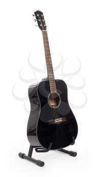 Black acoustic guitar on stand, isolated on a white background