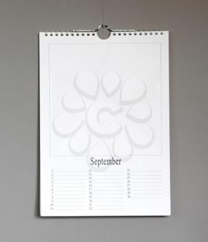 Simple old birthday calendar hanging on a grey wall, copy space - September
