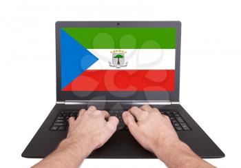 Hands working on laptop showing on the screen the flag of Equatorial Guinea