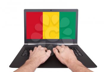 Hands working on laptop showing on the screen the flag of Guinea