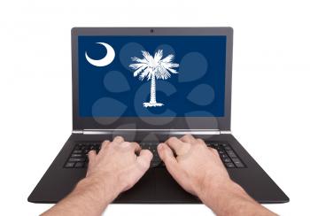 Hands working on laptop showing on the screen the flag of South Carolina