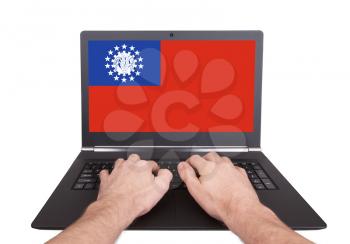 Hands working on laptop showing on the screen the flag of Myanmar