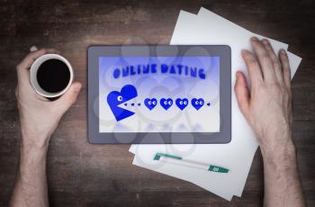 Online dating on a tablet - concept of love, blue pacman eating hearts