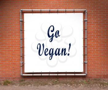 Large message written on white plastic, on a wall - Go vegan