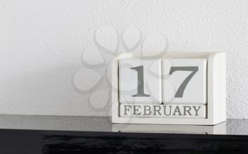 White block calendar present date 17 and month February on white wall background
