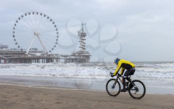 Scheveningen, The Netherlands - 30 December 2017: Cyclist on the beach in Scheveningen, defying a winter storm.
