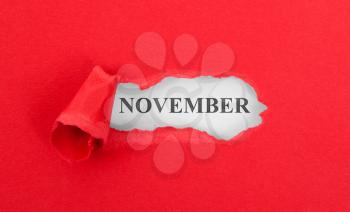 Text appearing behind torn red envelop - November