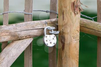 Locked wooden fence door with round padlock