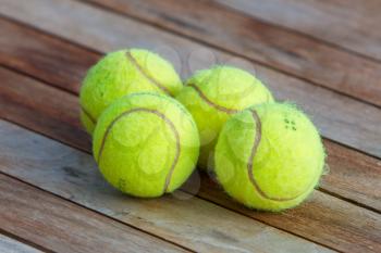 Four tennis balls isolated on a wooden table, selective focus
