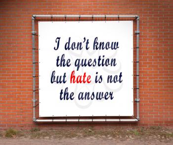Large banner with inspirational quote on a brick wall - I don't know the question but hate is not the answer
