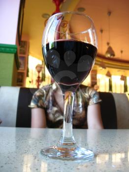 Glass of wine on a table at restaurant and the girl on a background