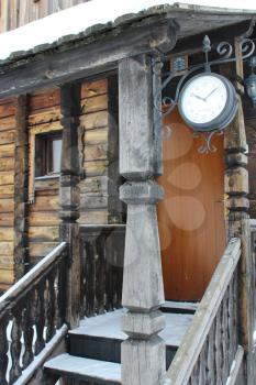 Porch of the wooden house with clock at the entrance