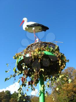 people made artifisial nest of storks on the blue sky background