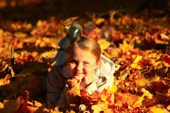little girl laying in yellow leaves in the autumn park