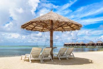 MALDIVES - JUNE 24, 2018: Wooden sunbed and umbrella on tropical beach in the Maldives at summer day
