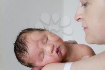 Cute infant sleeping on the mother’s shoulder