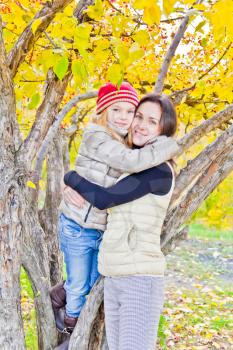 Photo of mother and daughter in autumn sitting on tree
