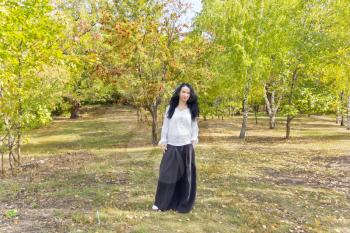 European woman with black hair walking in autumn park