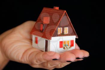 Image of dollhouse in human hand on black background