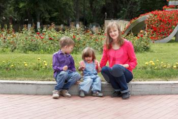 Mother with boy and baby girl sitting in summer park