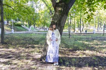 Pregnant woman with brown standing near tree in summer
