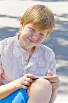 Blonde smiling boy with cellular phone in summer