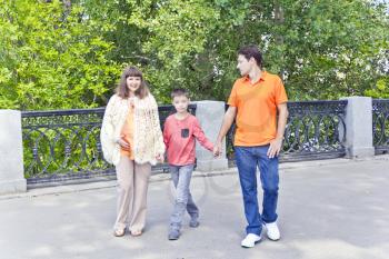 Walking family mother and son with father in summer embankment