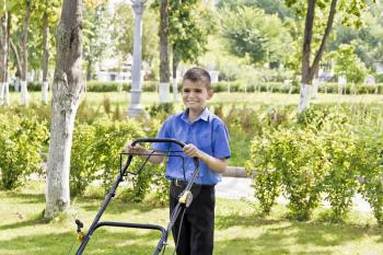 Cute smiling boy are working with lawn mower in summer