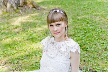 Beautiful bride in white dress sitting on the green grass