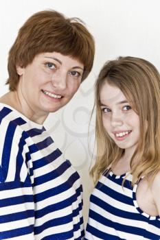 Happiest mother and daughter near white wall in striped clothes