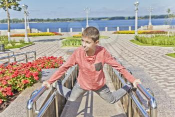 Teenager boy exercise at embankment in summer