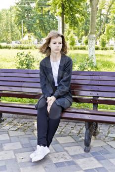 Sad girl fourteen years old are sitting on the bench