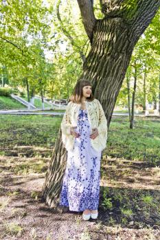 Pregnant woman with brown hair near tree in park