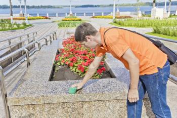 Man in orange is cleanning embankment bench