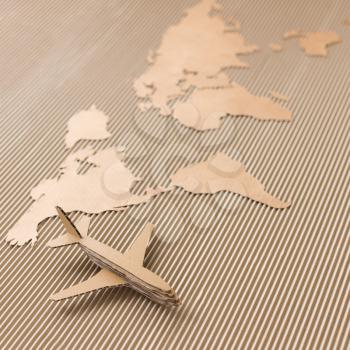 Airplane and world map made of cardboard. Square format, selective DOF