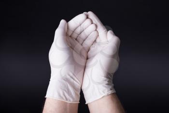 Male hands in latex gloves encircling, holding gesture. Showing or presenting. Dark background. Place for a concept.